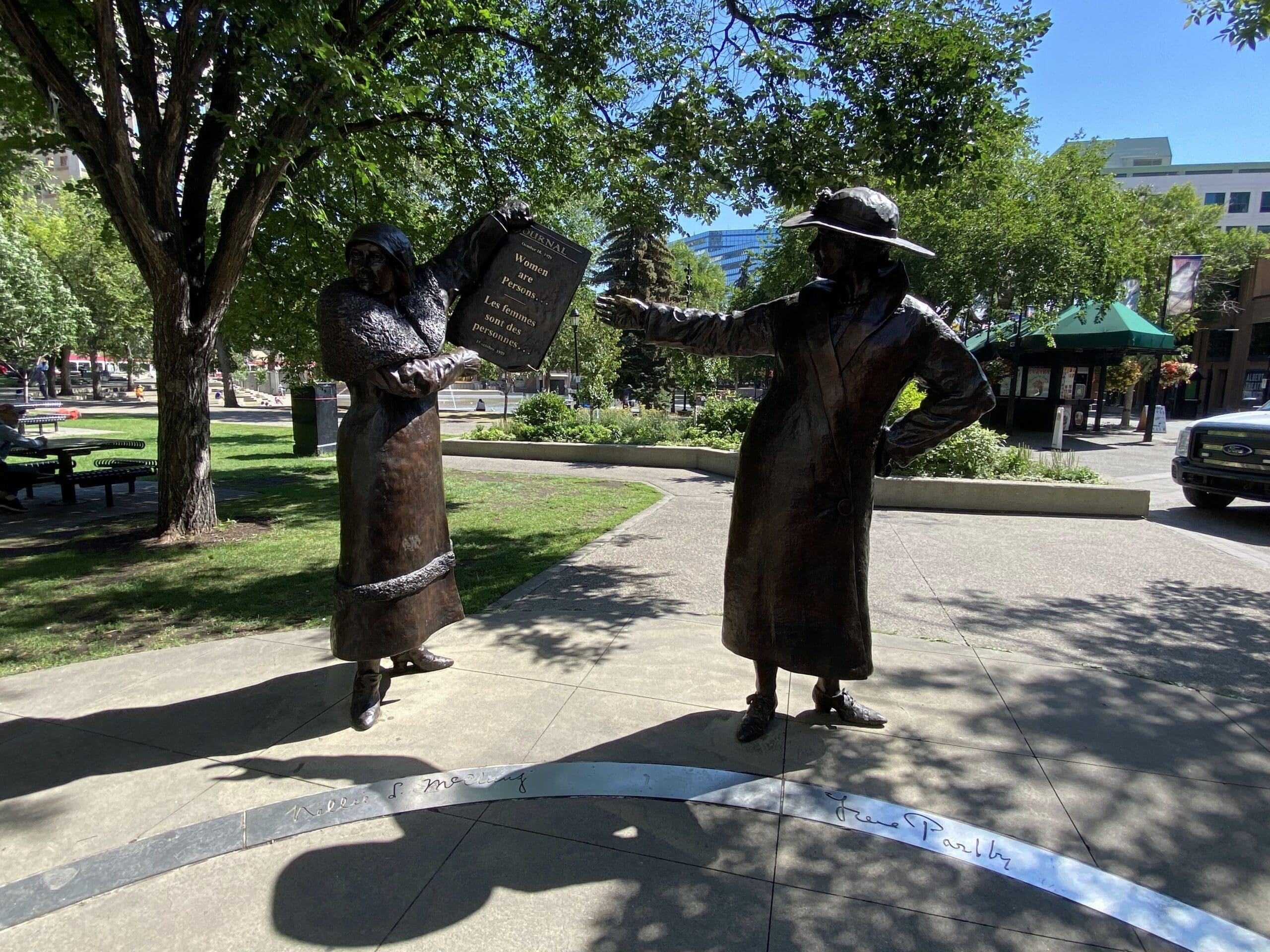Part of the Famous 5 Statues with their names written on the inner circle "Nellie McClung and Irene Parlby", holding a document which states in English and French - Women are Persons