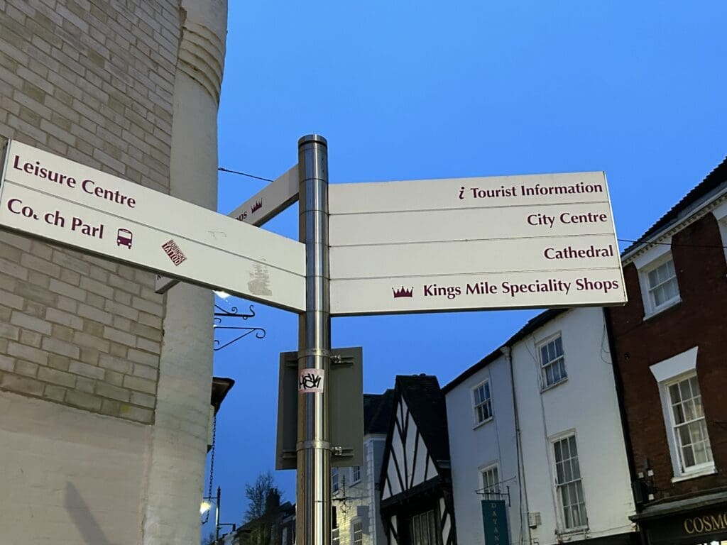 Signage near the Crooked House indicates how to get to Tourist Information, City Centre, Cathedral and the Kings Mile.